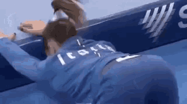 a woman in a blue jacket is laying on a blue couch .