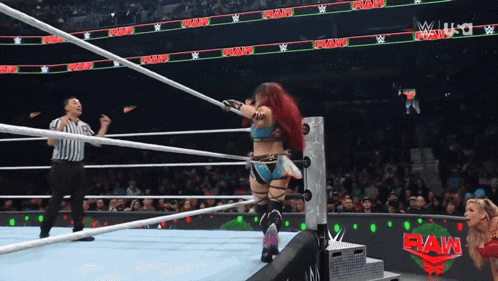 a woman in a wrestling ring with the word raw on the screen behind her
