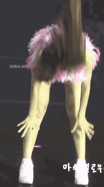 a woman wearing a pink feathered skirt and white sneakers is dancing on a stage .