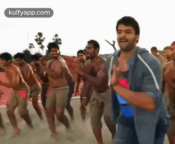 a group of men without shirts are dancing in the dirt .