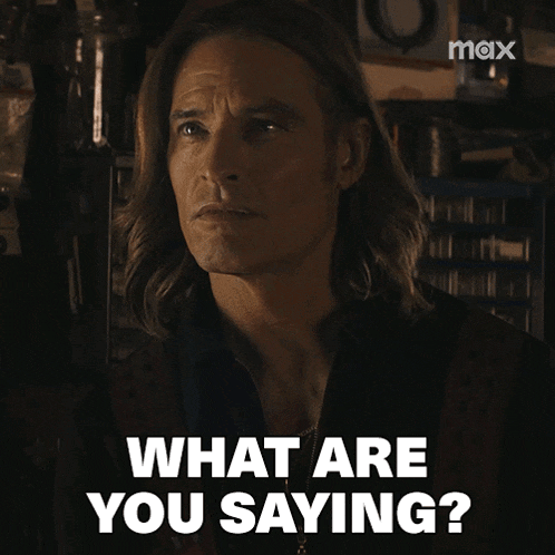 a man with long hair says what are you saying in white letters