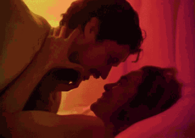 a man and a woman are kissing in a bed with a green light behind them