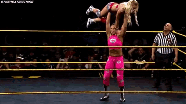two women are wrestling in a ring and one is holding the other up in the air .