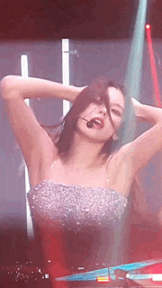 a woman in a strapless dress is dancing on a stage with her hands in her hair .