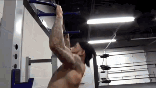 a man is doing pull ups on a bar in a gym without a shirt on .