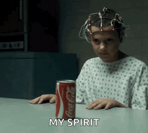 a girl in a hospital gown is sitting at a table with a can of coca cola