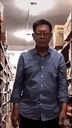 a man wearing glasses and a blue shirt is standing in a store ..
