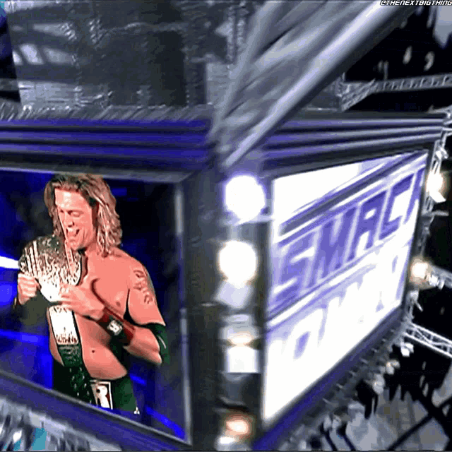 a wrestler is holding a trophy in front of a sign that says smackdown on it