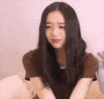 a woman with long black hair is sitting on a couch