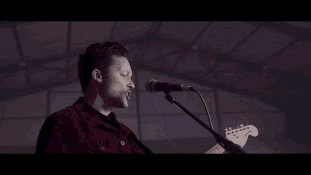 a man is singing into a microphone while playing a guitar .