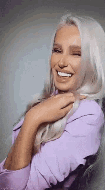 the woman is wearing a purple shirt and smiling .