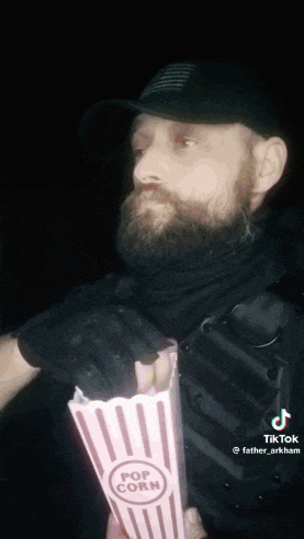 a man with a beard is holding a bag of popcorn .