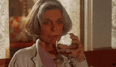 a woman is drinking a glass of wine from a wine glass .