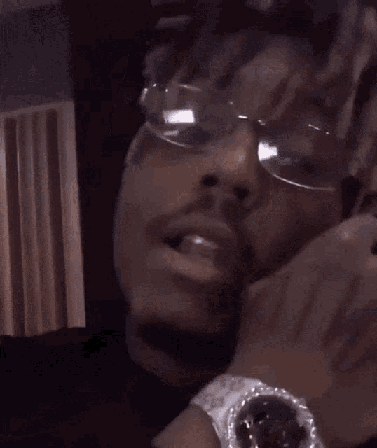 a close up of a man wearing glasses smoking a cigarette