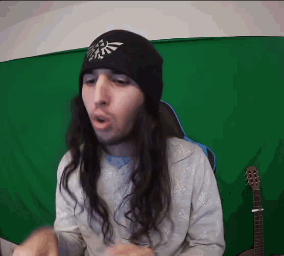 a man with long hair wearing a beanie with a zelda logo