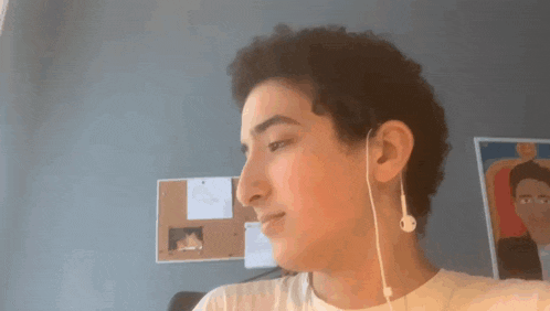 a young man wearing a pair of ear buds looks at the camera