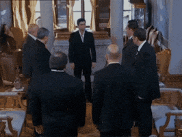 a group of men in suits are standing around a table