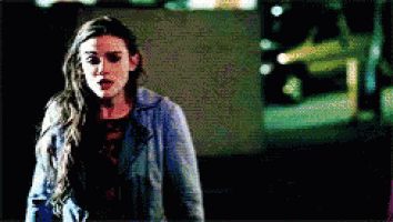 a woman in a denim jacket is standing in front of a car at night .