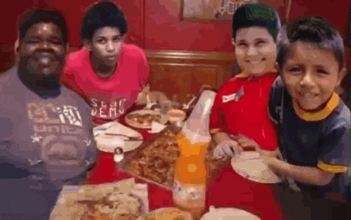 a group of young boys are sitting around a table eating pizza .
