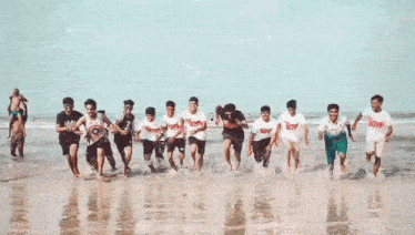 a group of young men are running on a beach wearing shirts that say boys