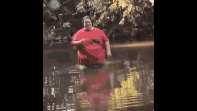 a man in a red shirt is standing in a flooded area .