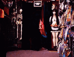 a skeleton and a woman are standing in a dark room with a sign that says no smoking