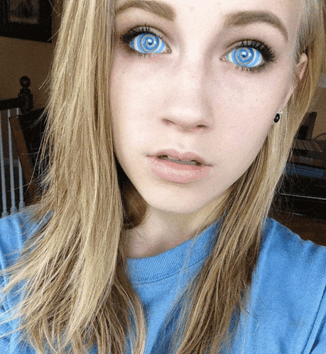 a girl with blue eyes and a blue shirt is looking at the camera