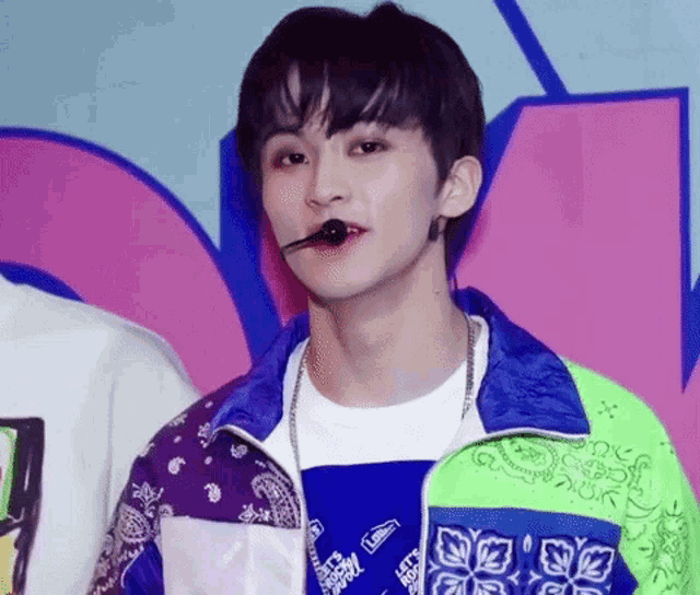 a close up of a person wearing a bandana and a jacket with a microphone in their mouth .