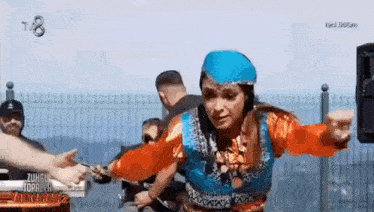 a woman in a traditional costume is dancing in front of a crowd .