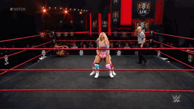 two women wrestle in a ring with the letters nxtuk on the bottom right