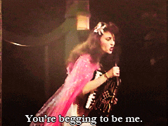 a woman singing into a microphone with the words " you 're begging to be me " next to her