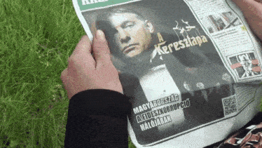 a person is reading a newspaper with a picture of a man on the front page