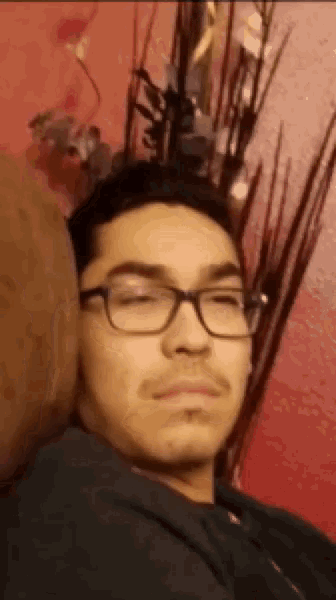 a young man wearing glasses is laying on a couch with his eyes closed