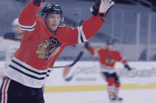 a hockey player wearing a red jersey with the blackhawks logo on it