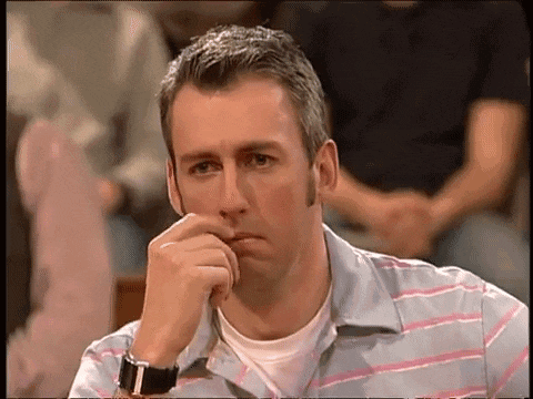 a man in a striped shirt with a watch on his wrist is sitting with his hand on his chin
