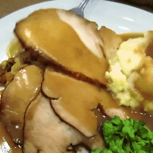 a white plate topped with turkey mashed potatoes gravy and green peas