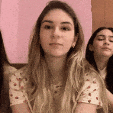 a woman wearing a strawberry shirt is sitting next to another woman .