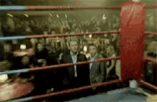 two men are standing in a boxing ring with a crowd watching