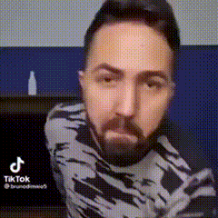 a man with a beard is wearing a black and white sweater and making a funny face .