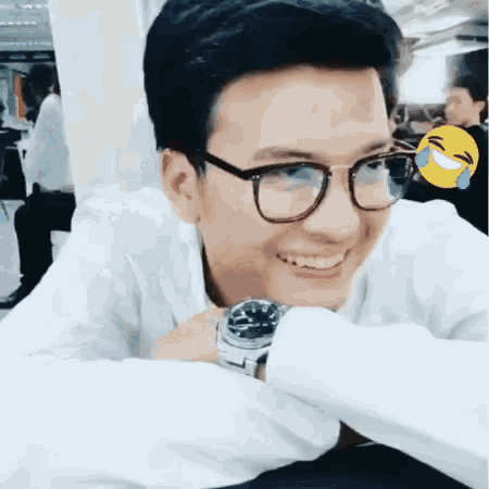 a young man wearing glasses and a watch is smiling and laughing .