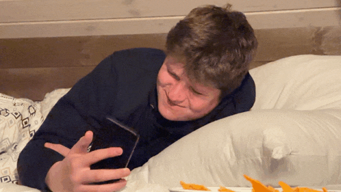 a man is laying on a bed looking at his cell phone