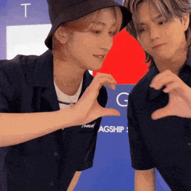two young men are making a heart shape with their hands in front of a sign that says tommy agship