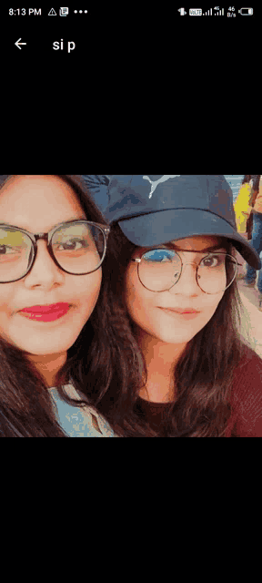 two girls wearing glasses and a black puma hat pose for a picture