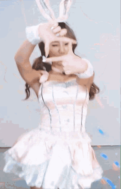 a woman in a pink dress is taking a picture of herself with her finger .