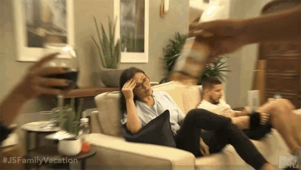 a woman is sitting on a couch with her hand on her head while someone pours a glass of wine