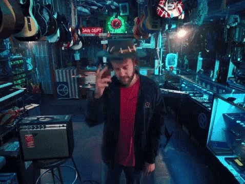 a man in a hat stands in front of a fender amplifier