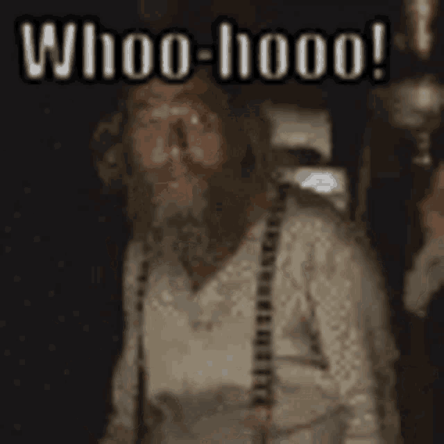 a man with a beard and suspenders is standing in a dark room and says whoo hoo !
