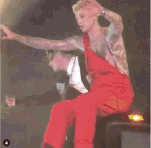 a man in red pants is sitting on a stage with his legs crossed .