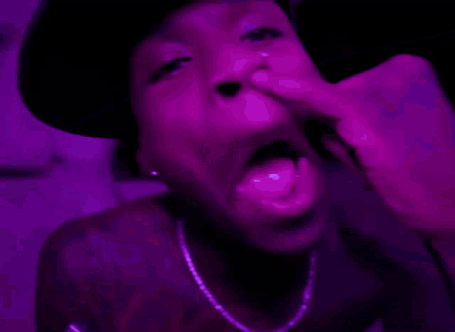 a man with braces on his teeth is sticking his tongue out in front of a purple light .
