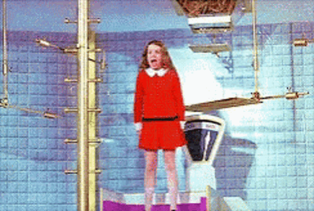 a little girl in a red dress is standing in front of a scale ..